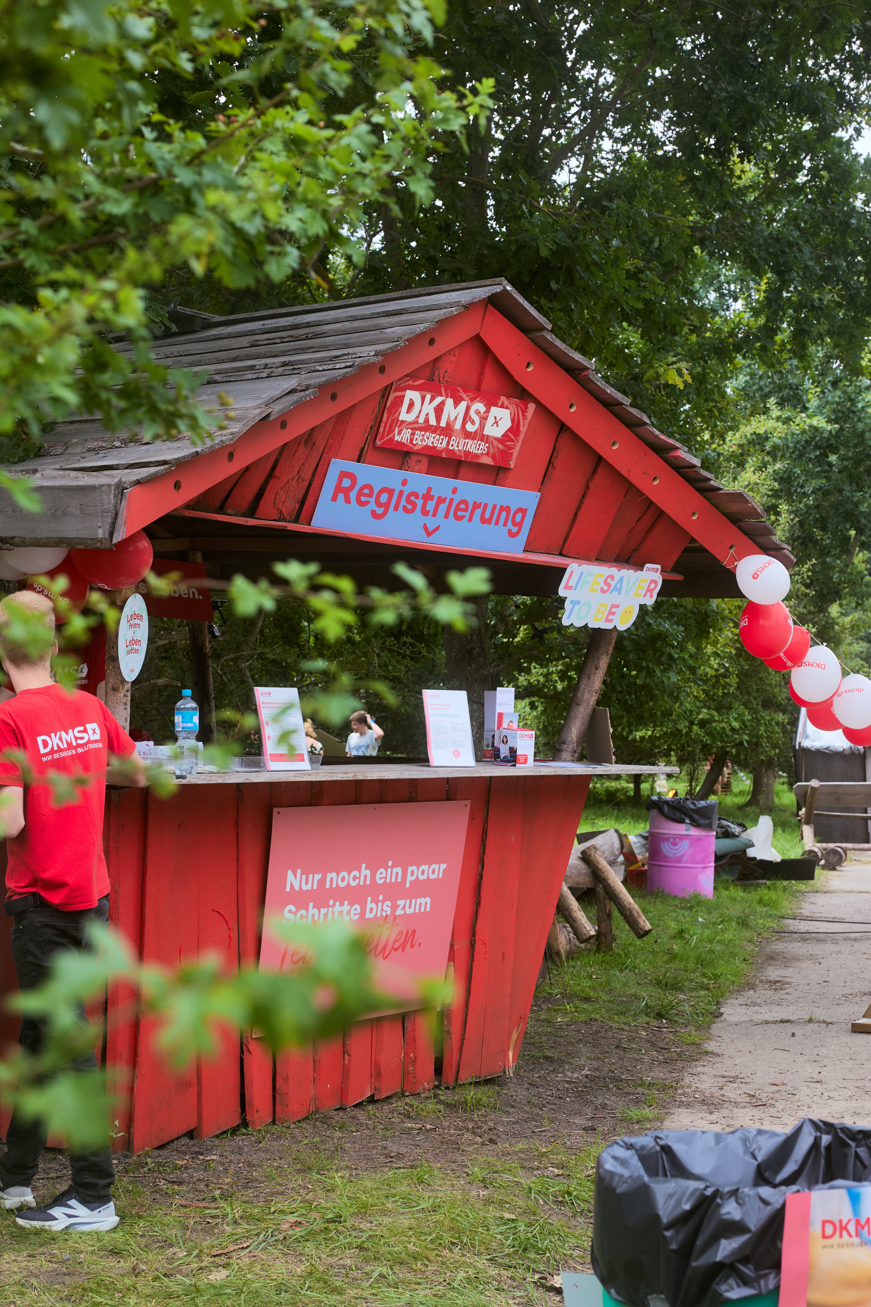 Ein Mann steht an einem kleinen roten Stand