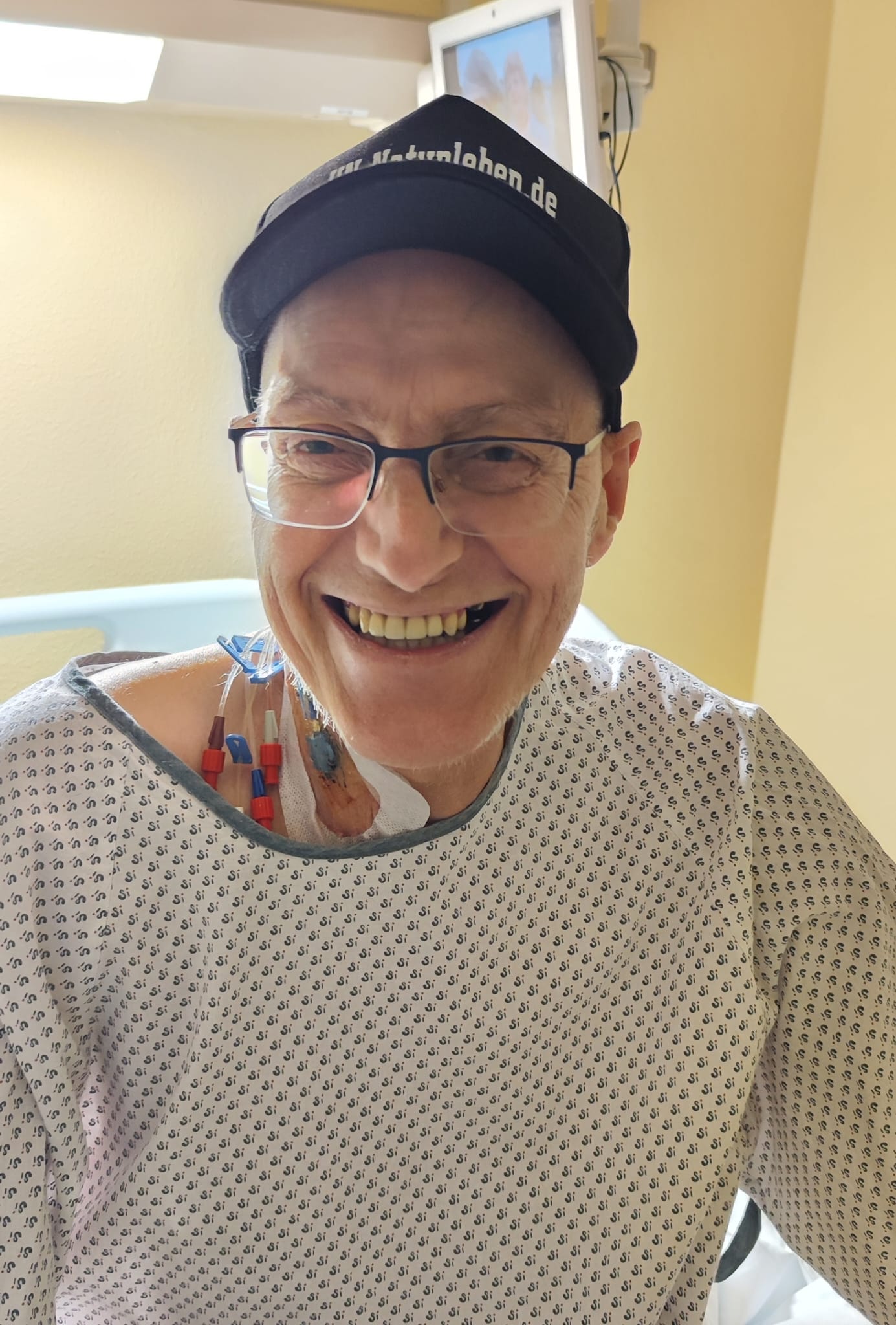 Lächelnder Mann mit Schildkappe und Patientenkittel