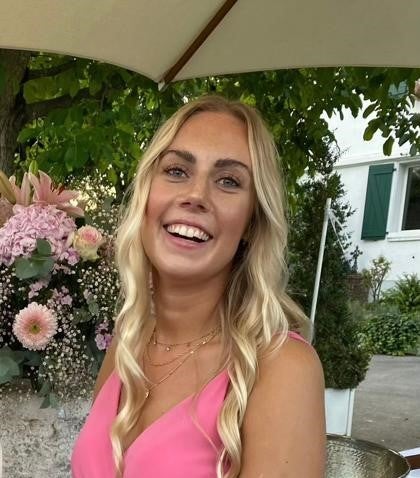 eine Frau mit pinkem Kleid lacht in die Kamera