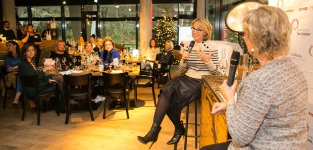 Eine Frau sitzt auf einem Barhocker und hält ein Mikrofon