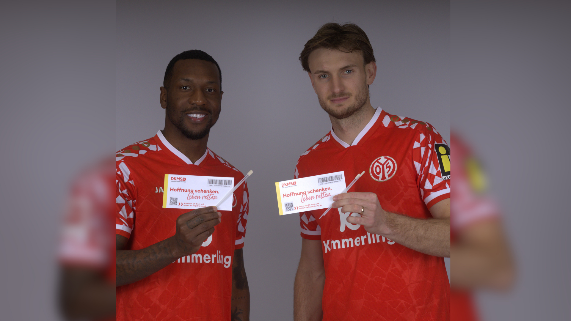 Zwei Spieler des Mainz 05 halten das Registrierungsset in die Kamera. 