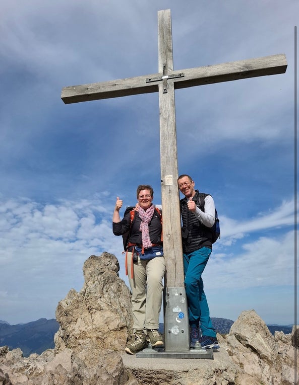 Bernd und seine Frau an einem Gipfelkreuz nach einer Wanderung. 
