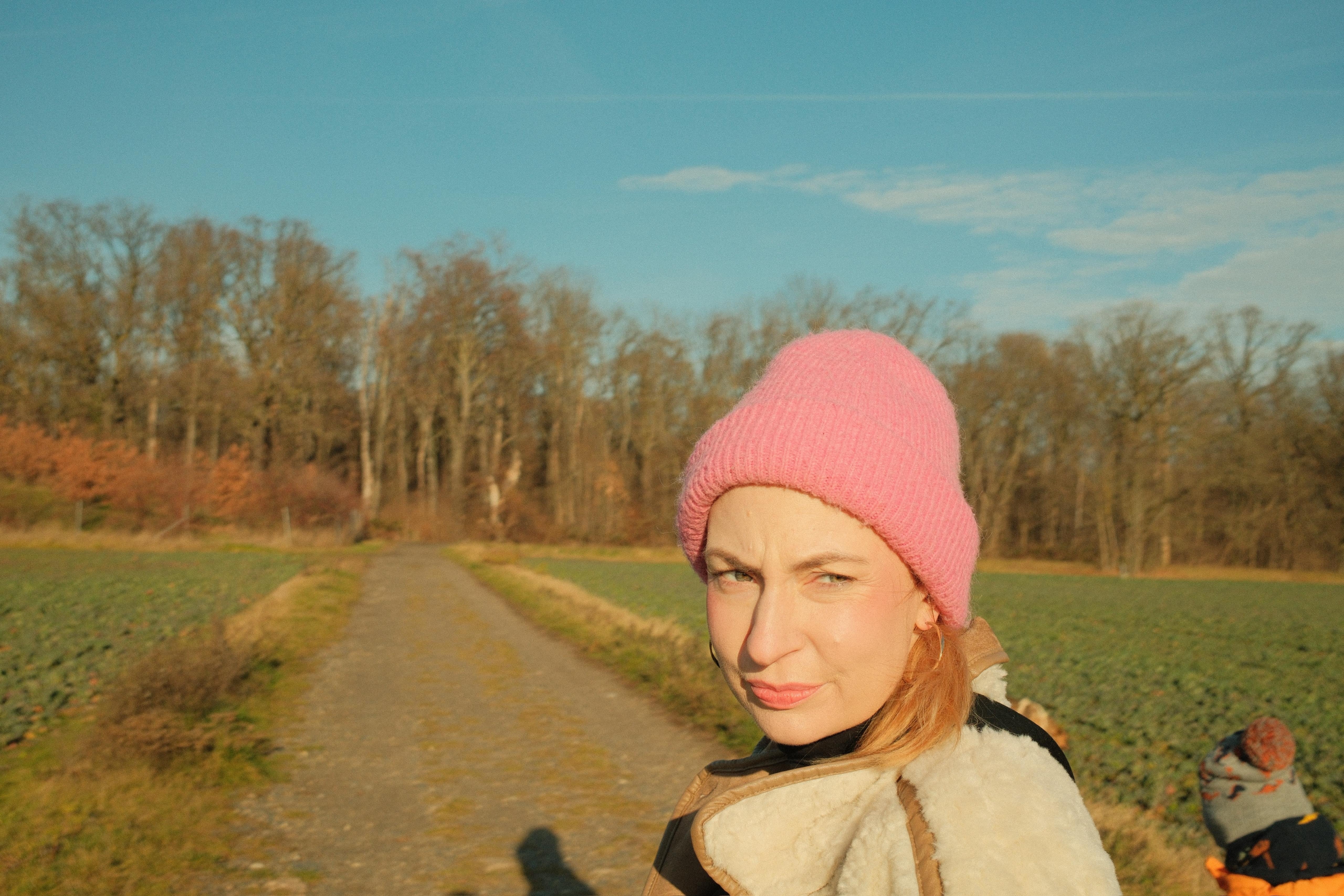 Franzi mit ihrer pinken Mütze, spaziert auf einem Feldweg. 