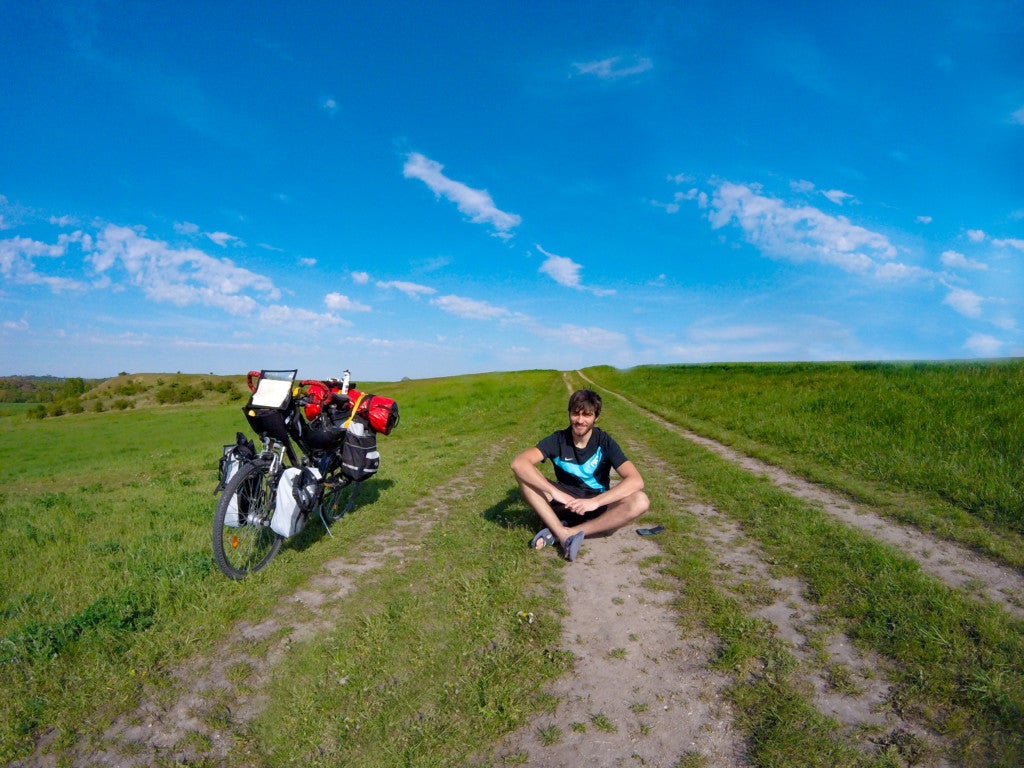 Ein Mann sitzt auf einem unbefestigten Feldweg mit einem Fahrrad