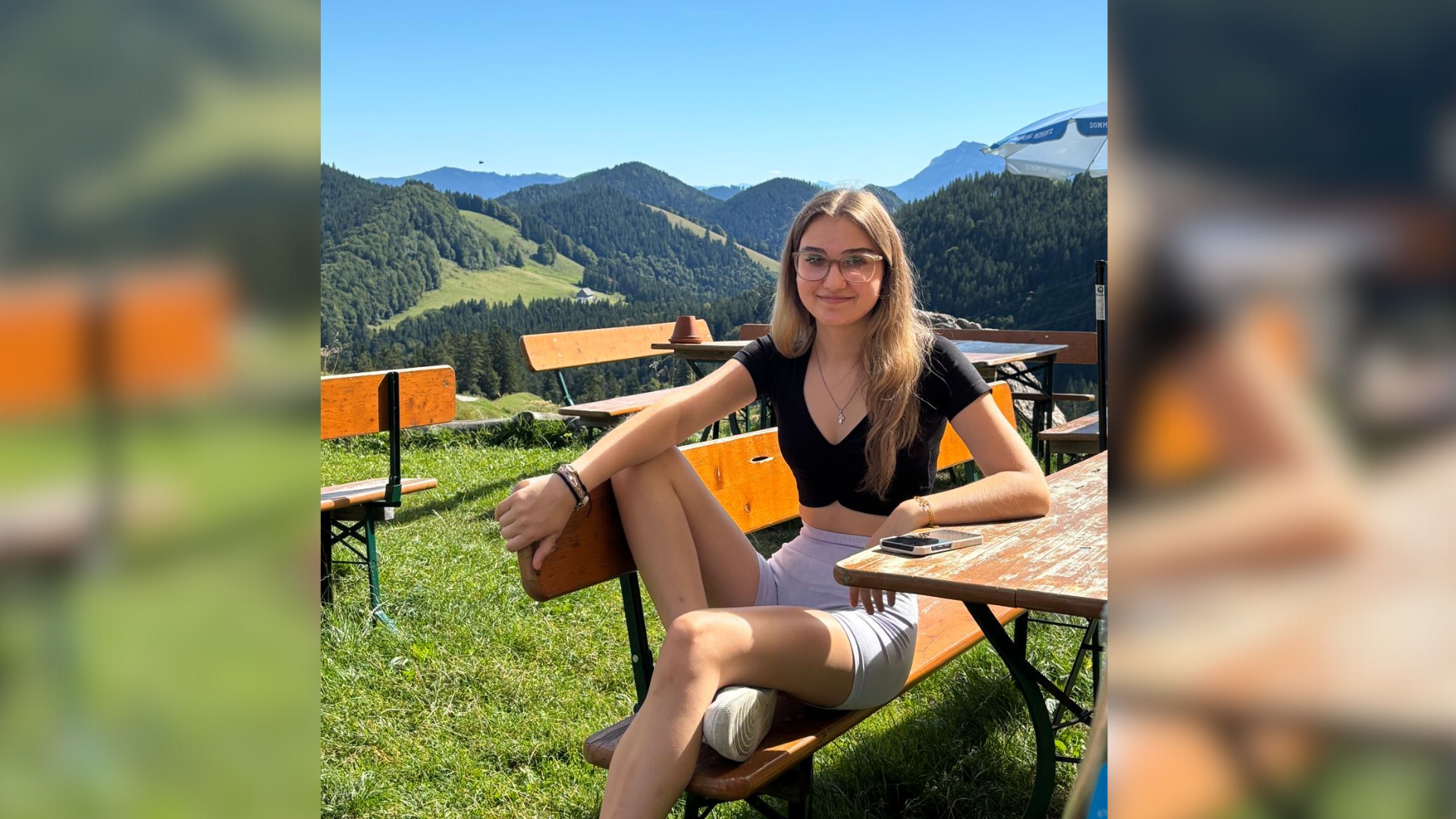 Eine junge Frau sitzt auf einer Bierbank in der Sonne.
