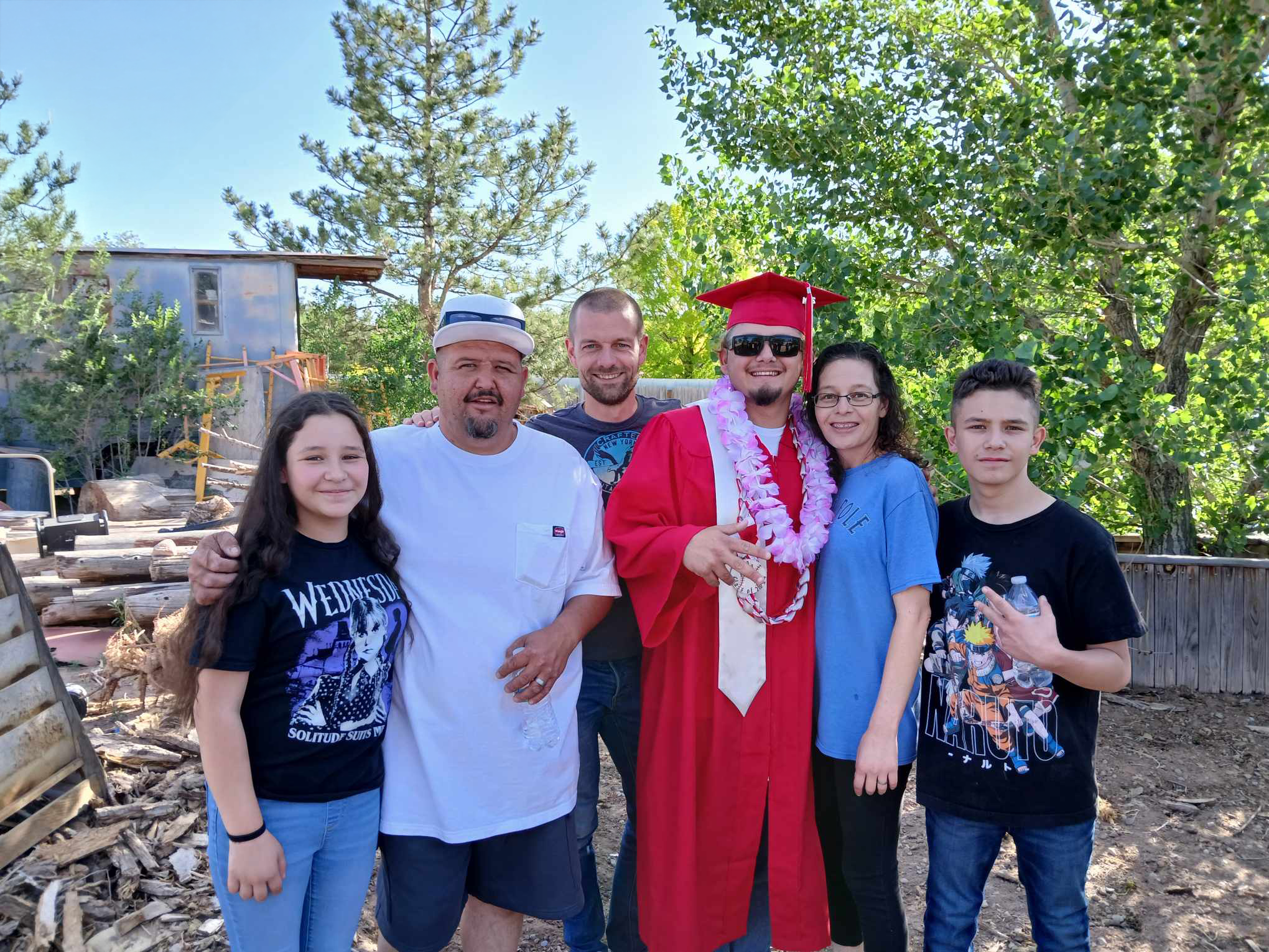 Gruppenbild mit sechs Personen. In der Mitte ein junger Mann in typischer Robe zum Anlass seines Highschool-Abschlusses