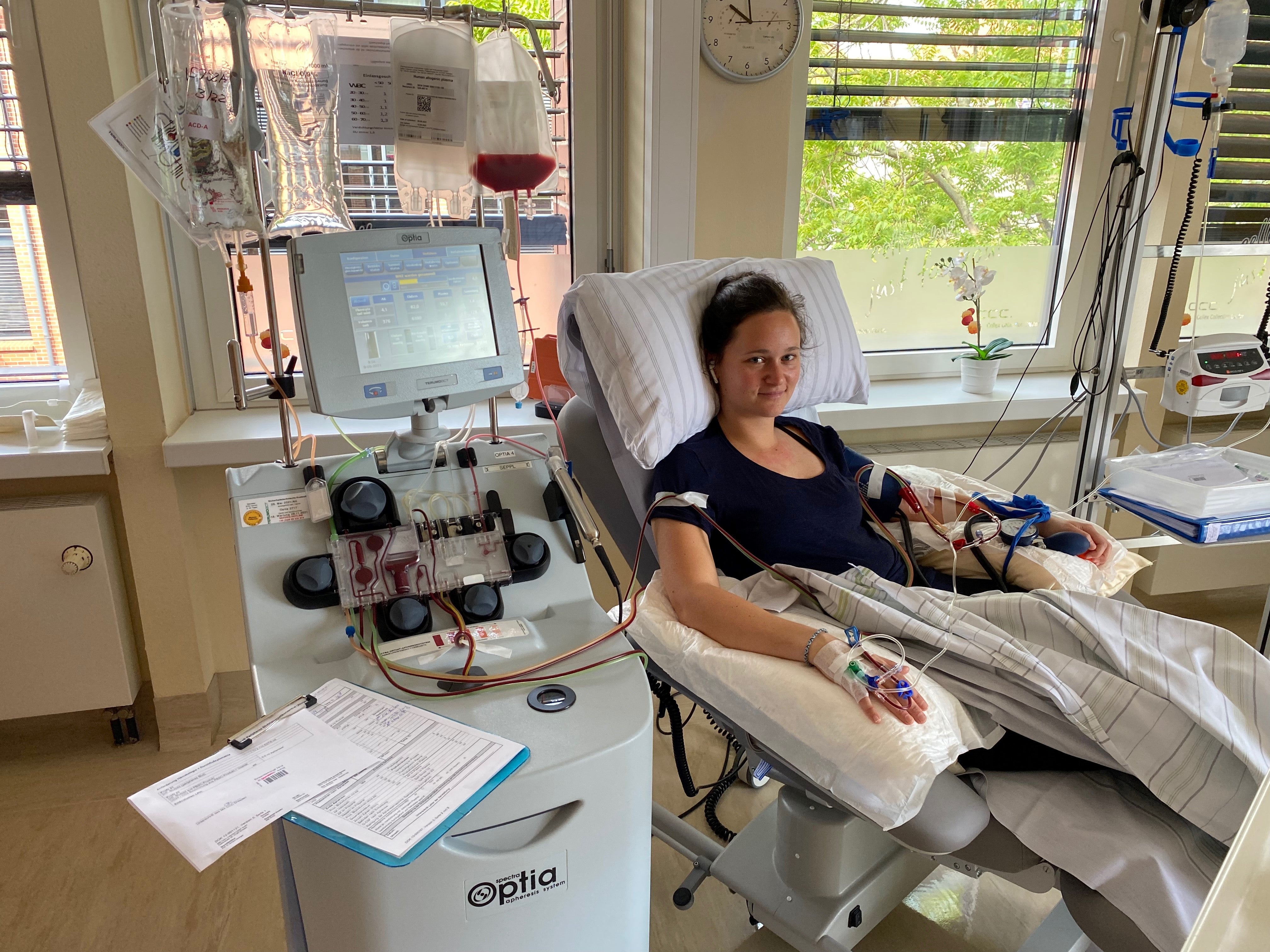 Eine Frau liegt während ihrer Stammzellspende in einem Bett, sie ist an ein Apherese-Gerät angeschlossen