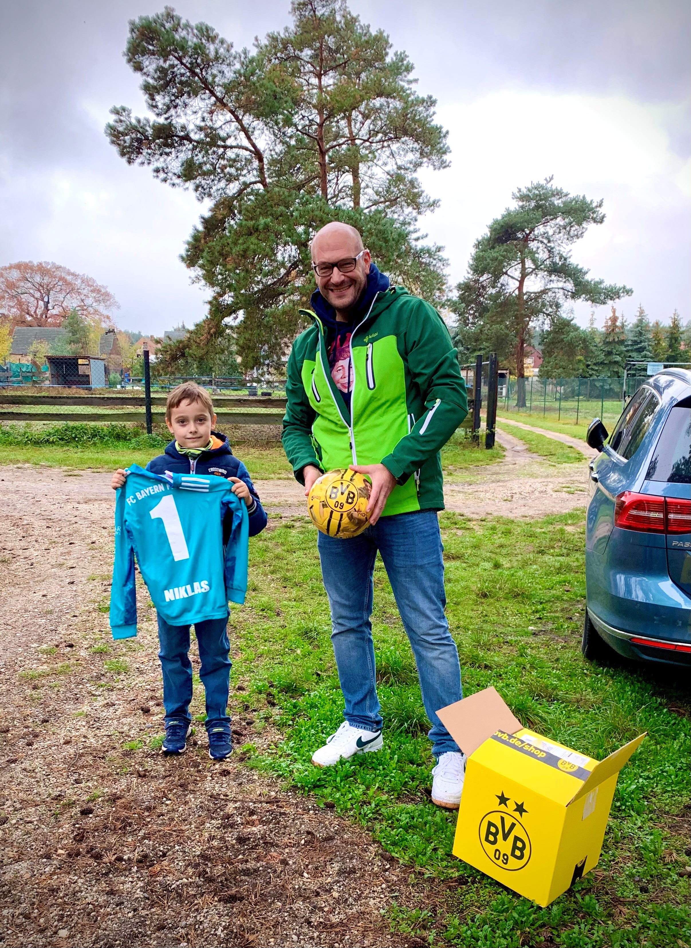 Ein Mann und ein Junge posieren für ein Foto, sie packen Geschenke aus, man sieht einen BVB Ball