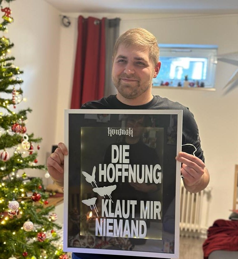 Ein Mann hält ein Schild vor einem Weihnachtsbaum