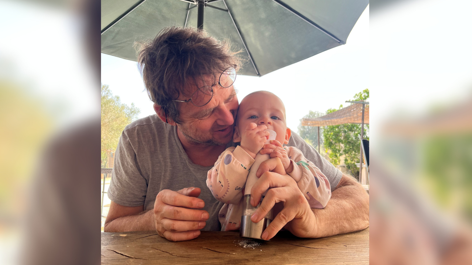 Ein Mann hält ein Baby unter einem Regenschirm