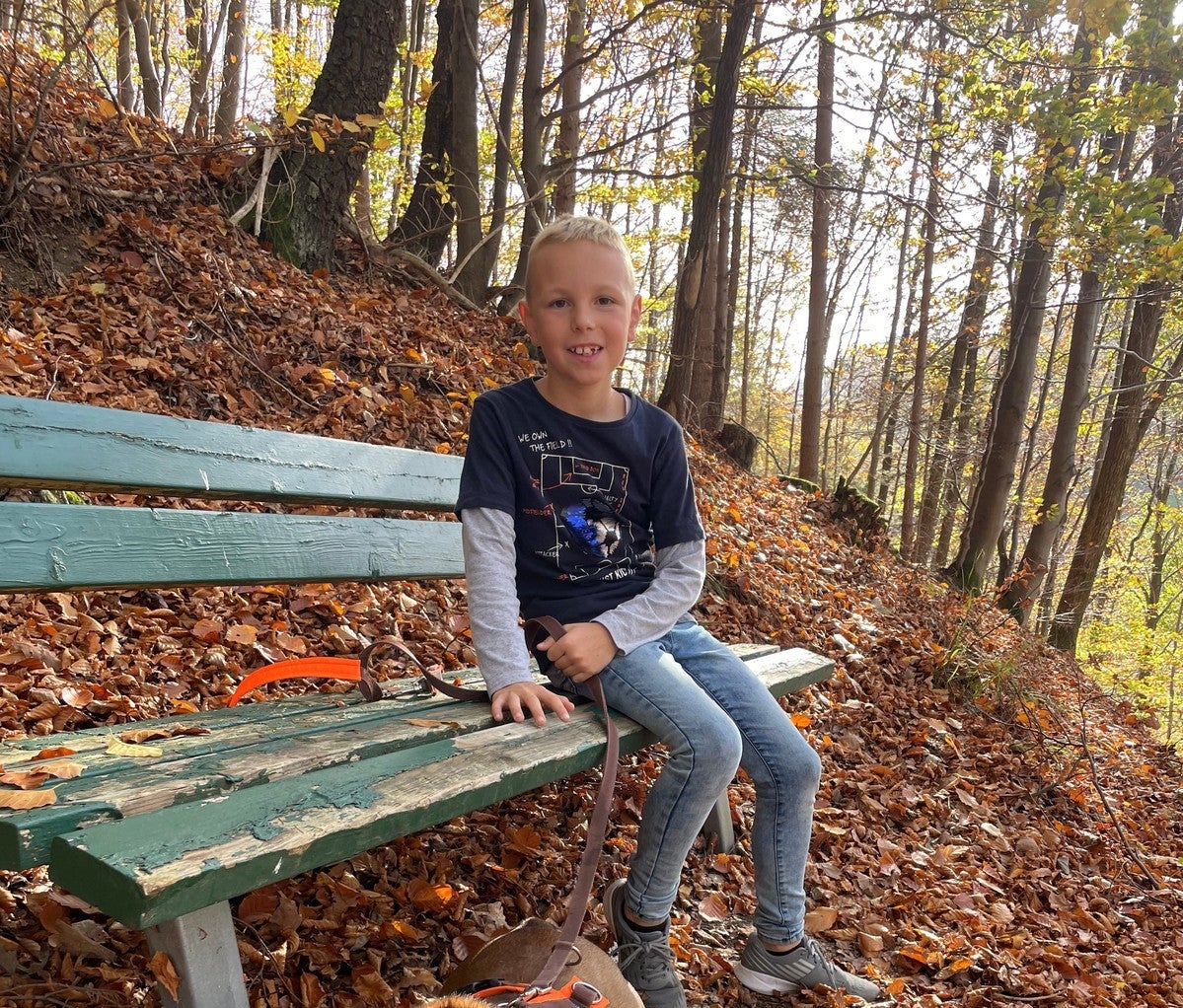 kleiner Junge sitzt auf einer Bank im Wald