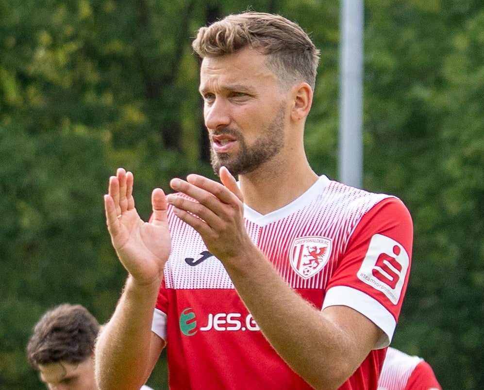 Ein Mann in einem rot-weißen Trikot klatscht