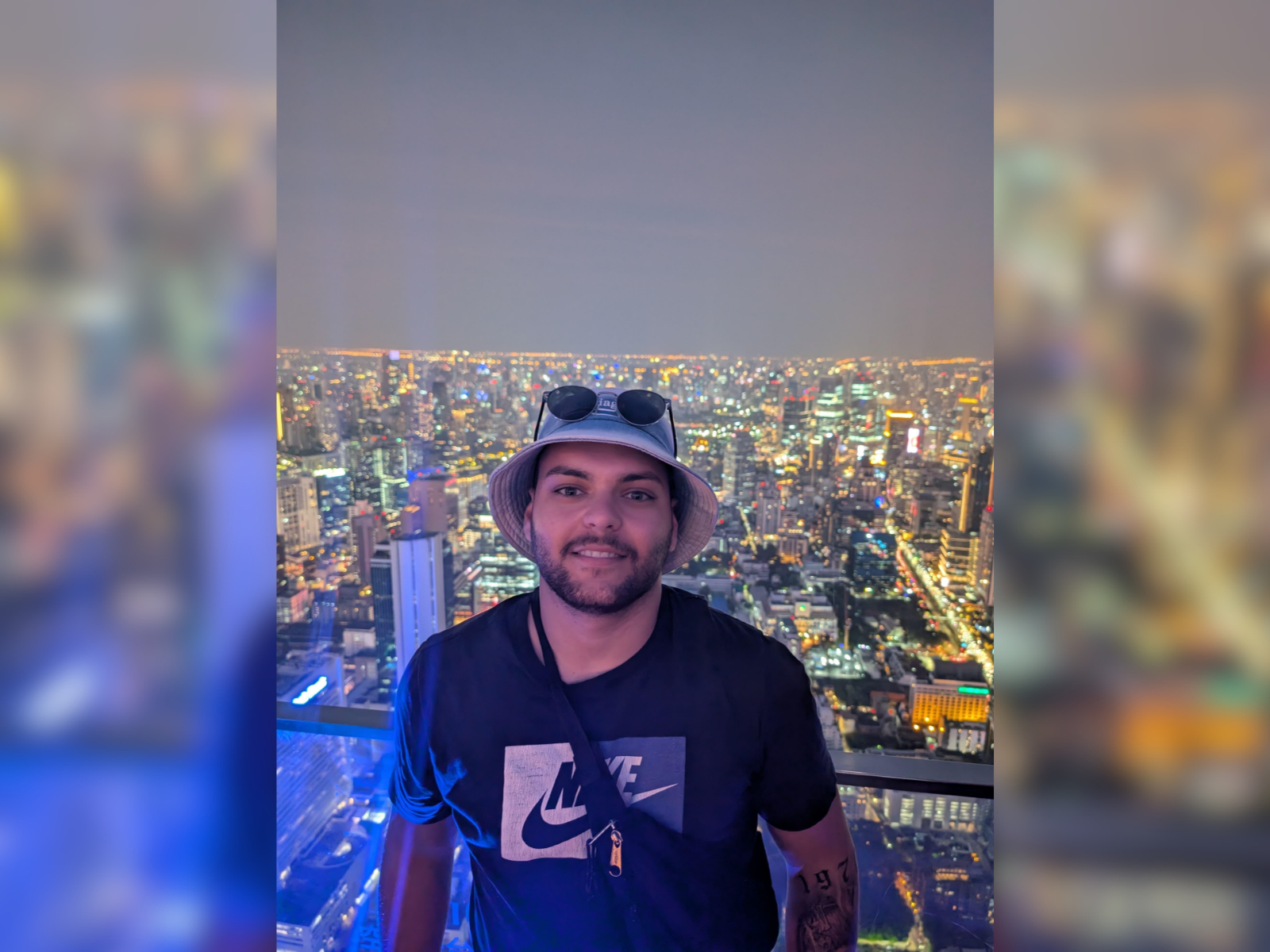 Patient Yasin steht auf dem Balkon vor einer erleuchteten Skyline  