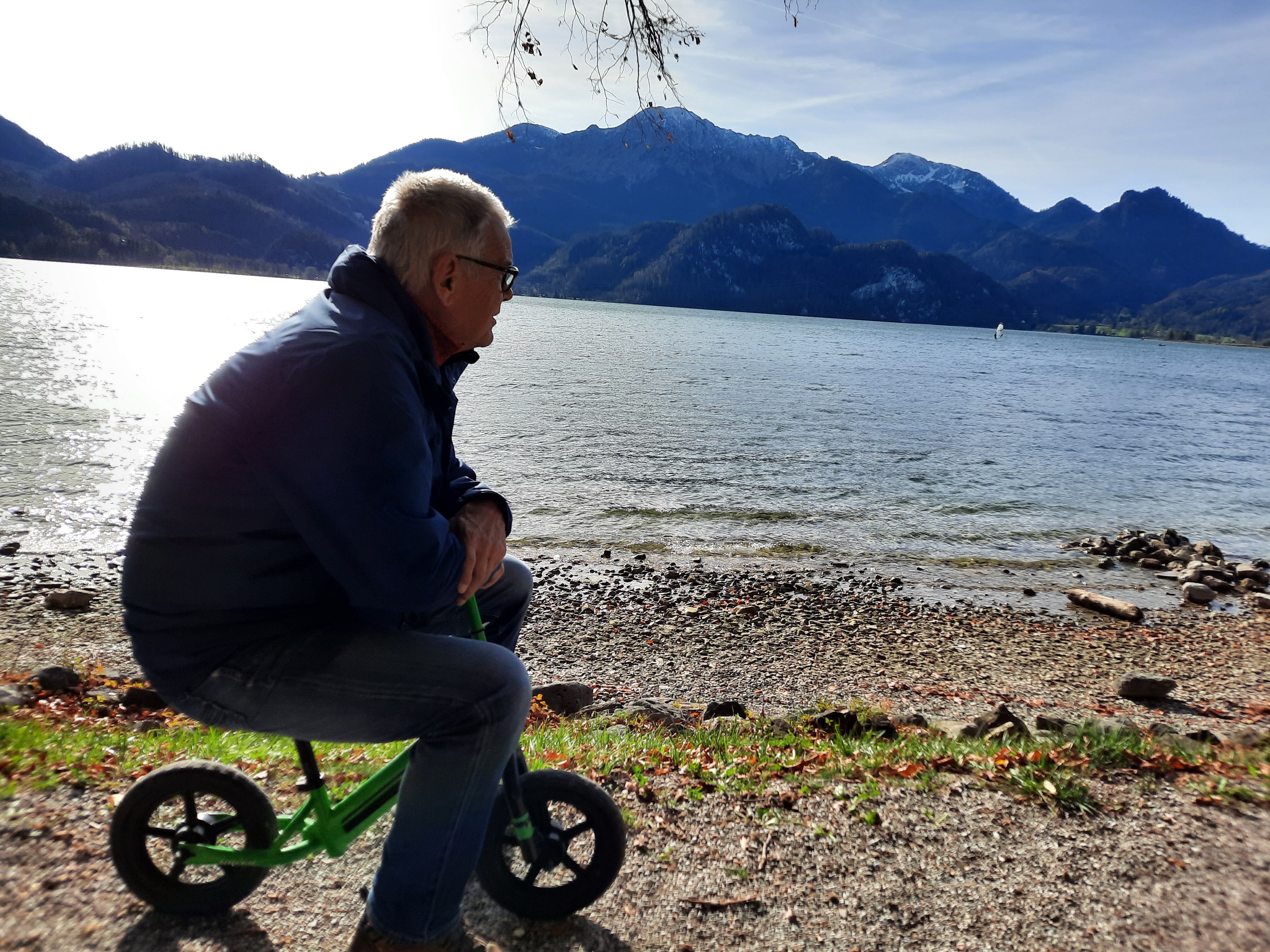 Ein Mann sitzt auf einem kleinen Fahrrad neben einem Gewässer