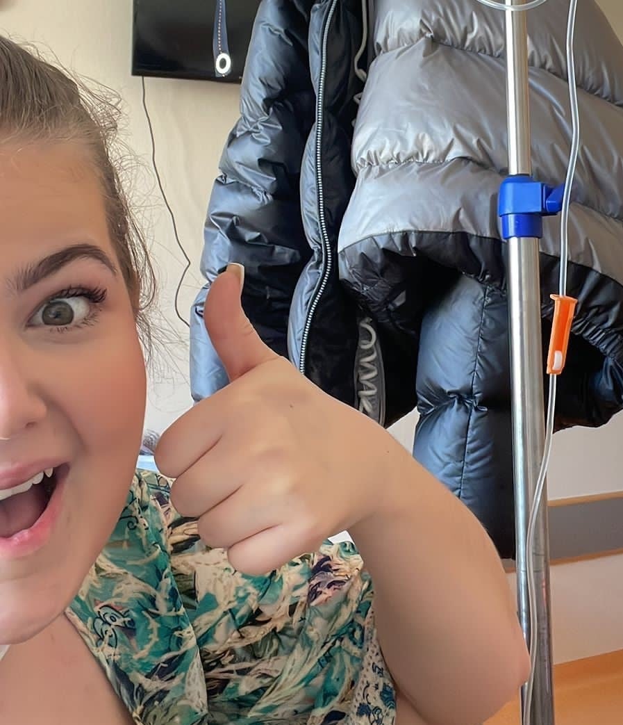 eine Frau lacht in die Kamera und macht ein Daumen hoch Symbol