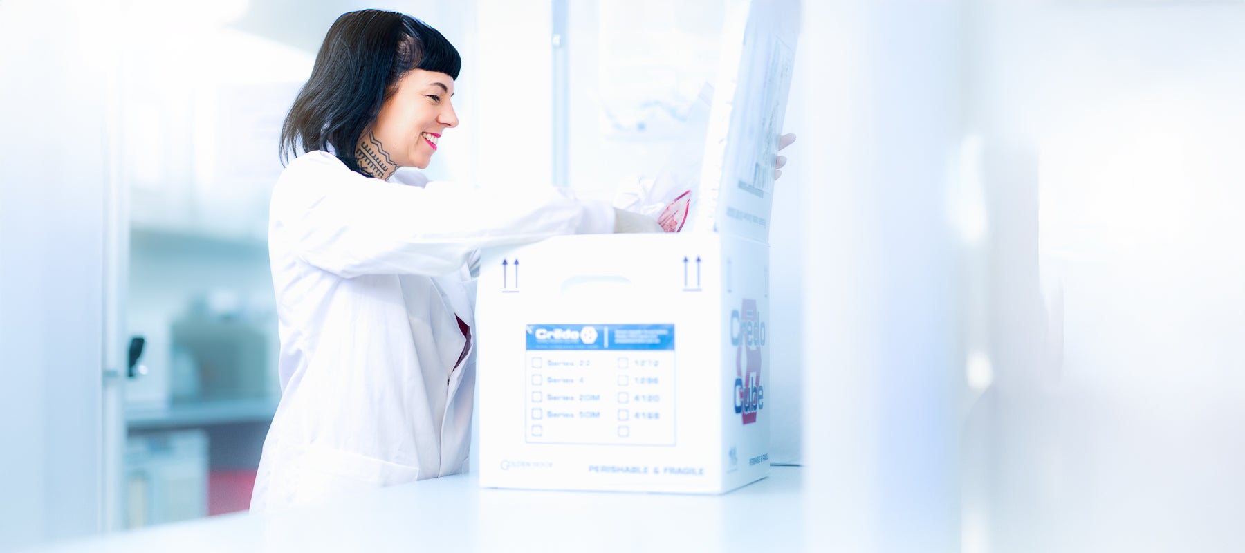 Eine Frau im weißen Kittel öffnet eine Box voller Spendenmaterial