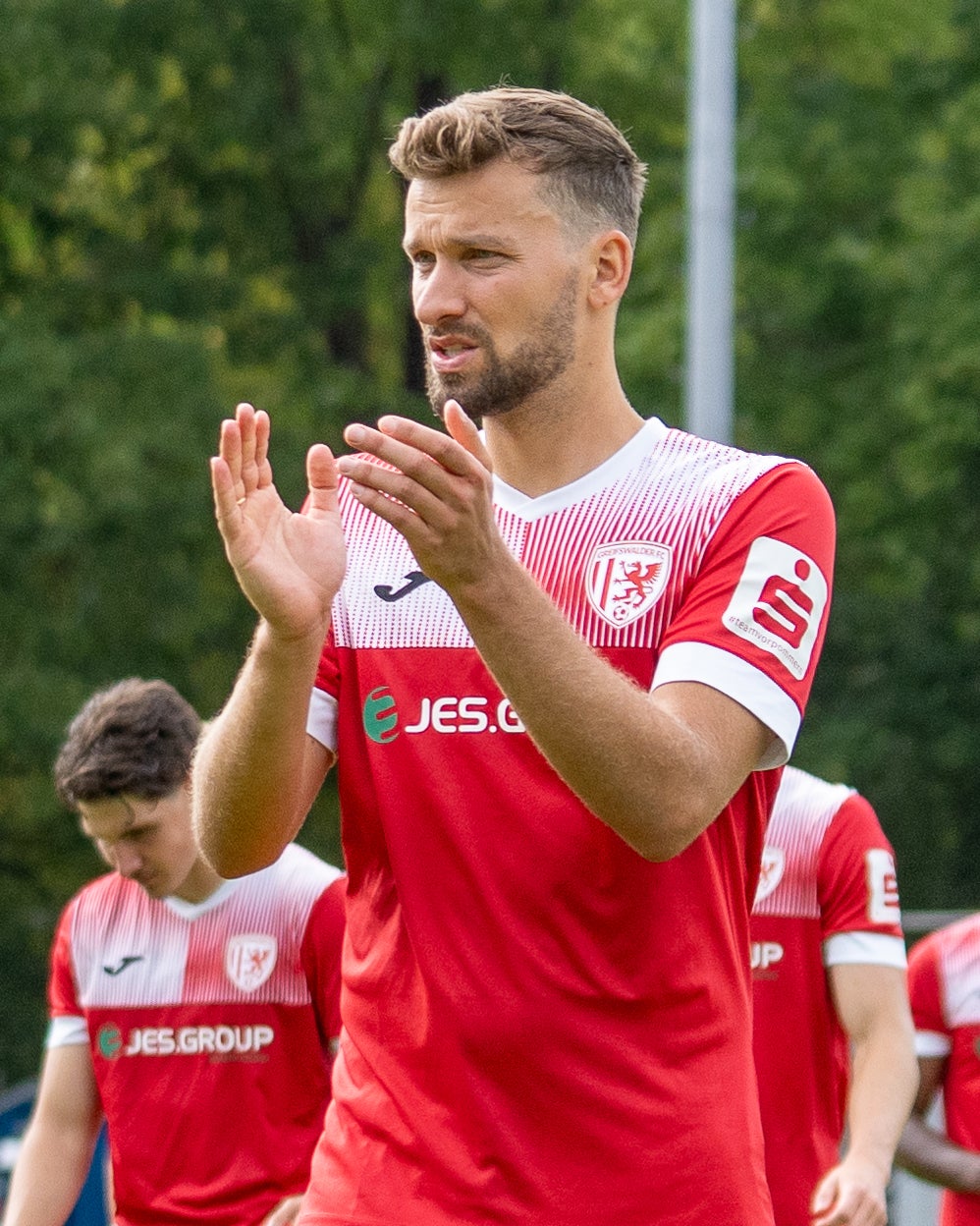 Ein Mann in einer roten Uniform klatscht