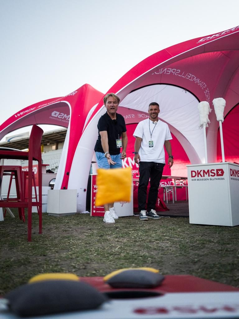 Zwei Männer stehen vor einem Zelt und spielen ein Spiel