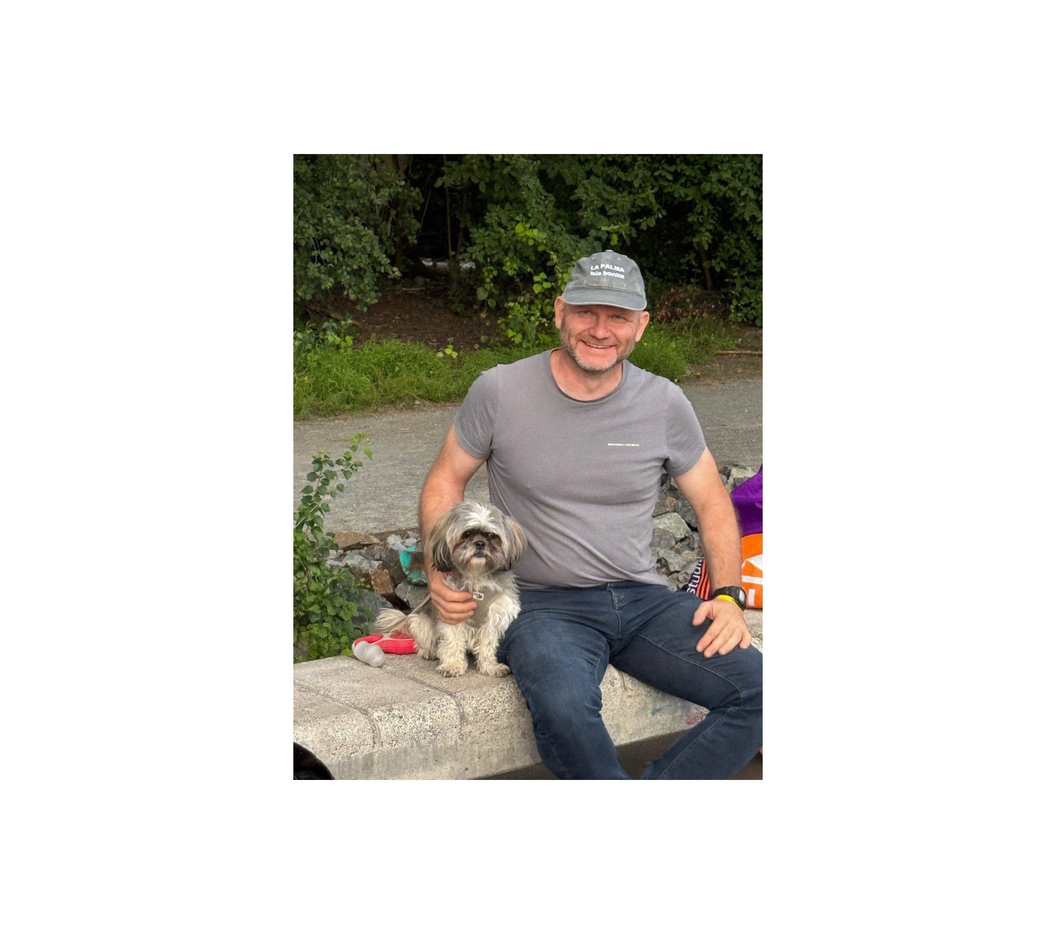 Ein Mann sitzt mit einem Hund auf einer Bank