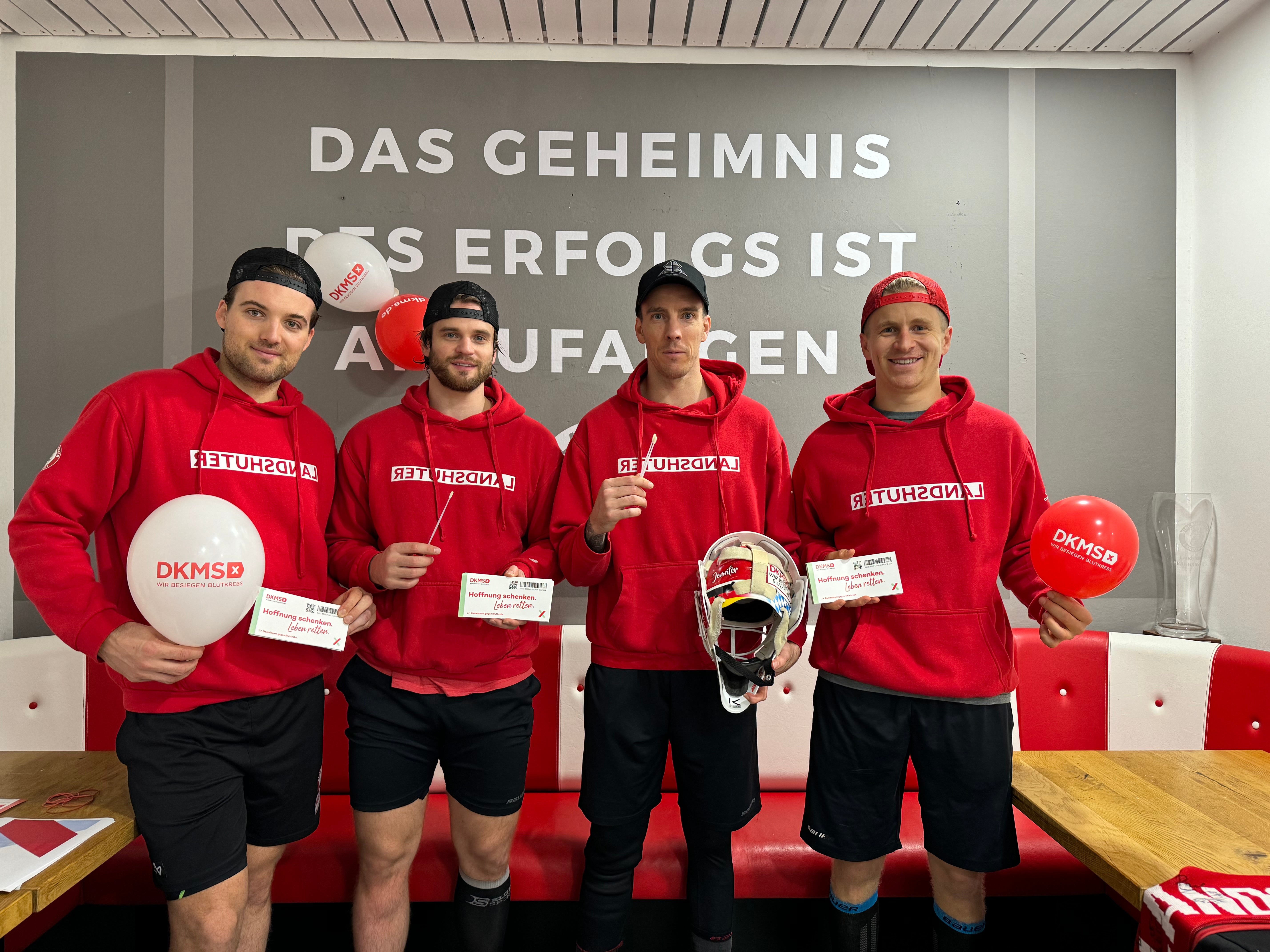 Eine Gruppe von Männern posiert mit DKMS-Ballons und Registrierungssets