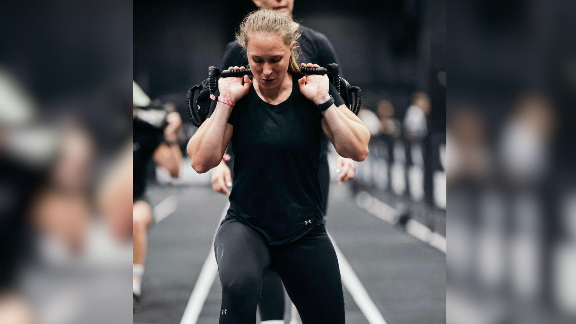 Eine Frau in schwarzem Hemd, die Riemen über ihre Schultern legt