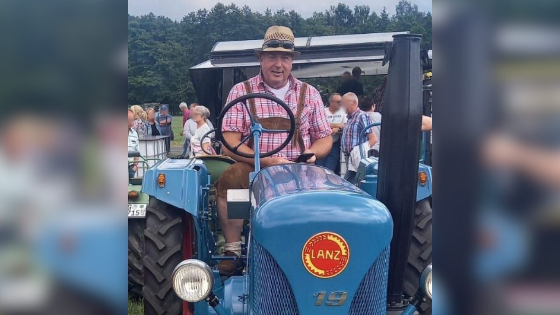 Ein Mann trägt Tracht und sitzt auf einem blauen Traktor.