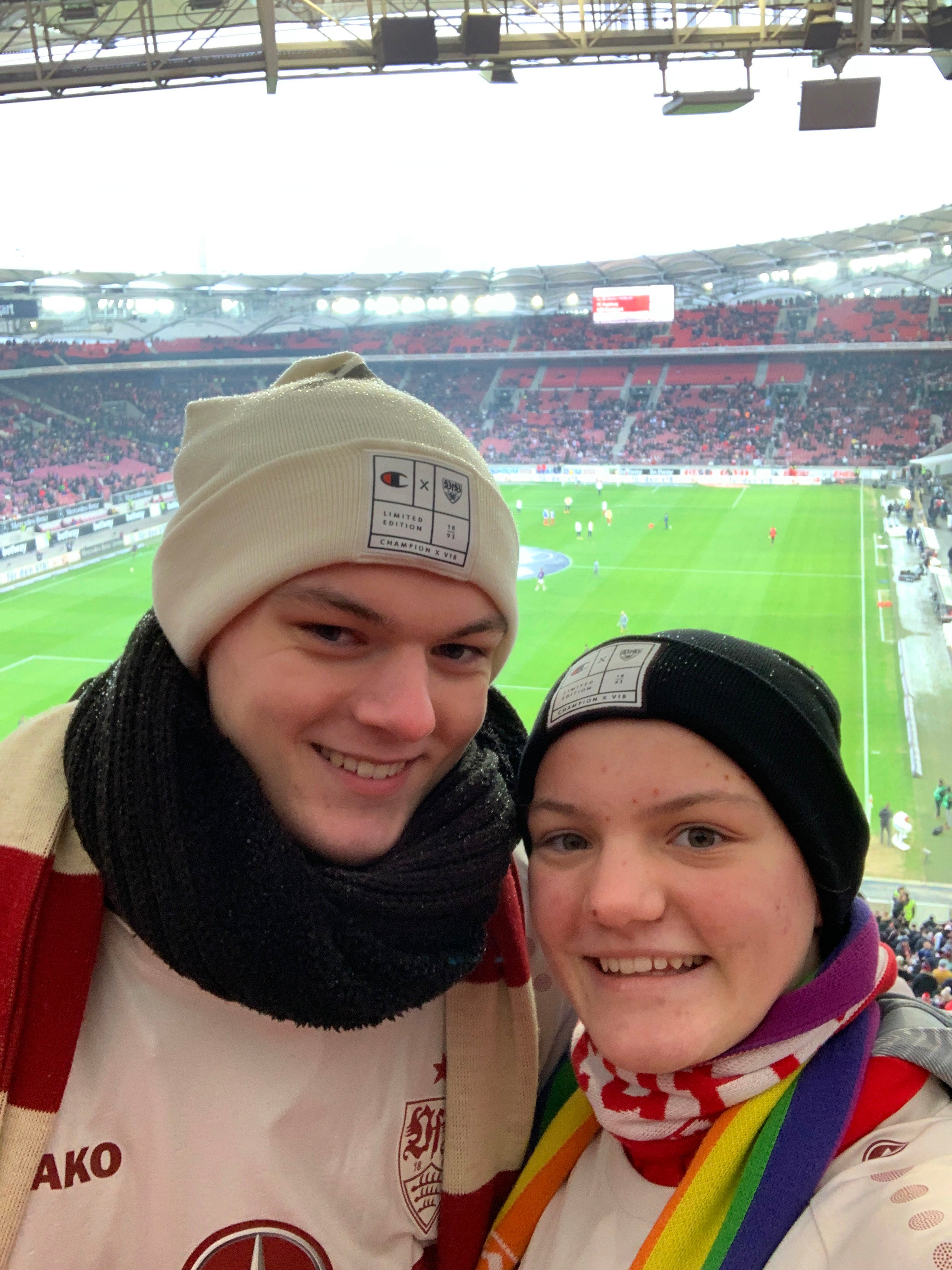 zwei Fußballfans posieren zusammen vor dem Fussballfeld