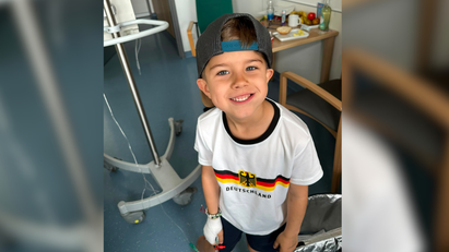 Ein Junge, der an eine Infusion angeschlossen ist und in die Kamera lächelt