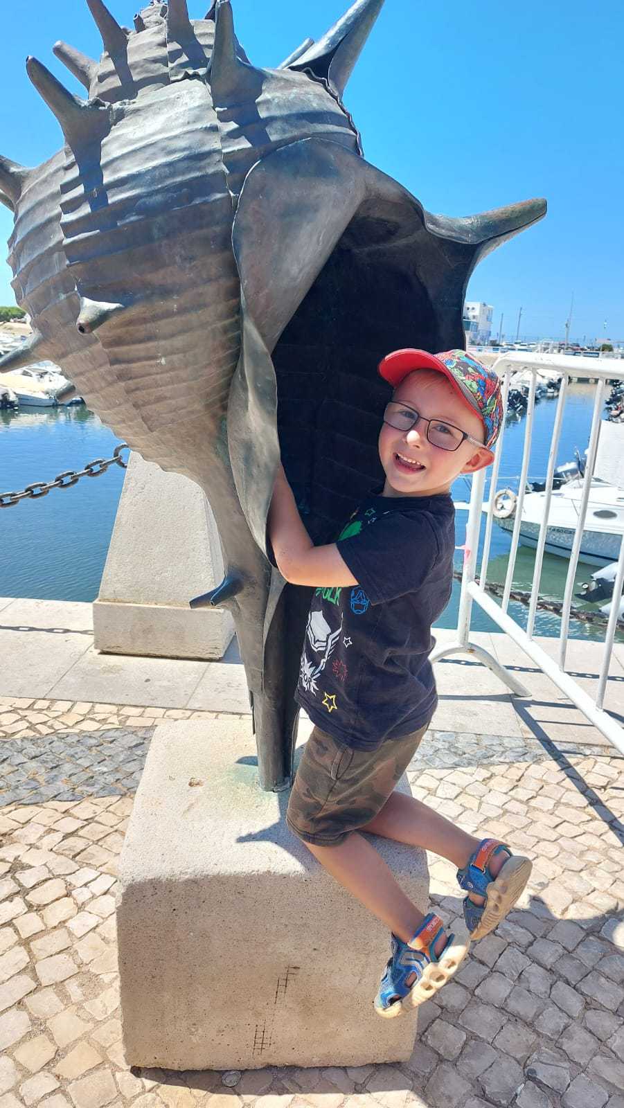 ein Junge posiert mit einer Muschel-Statue