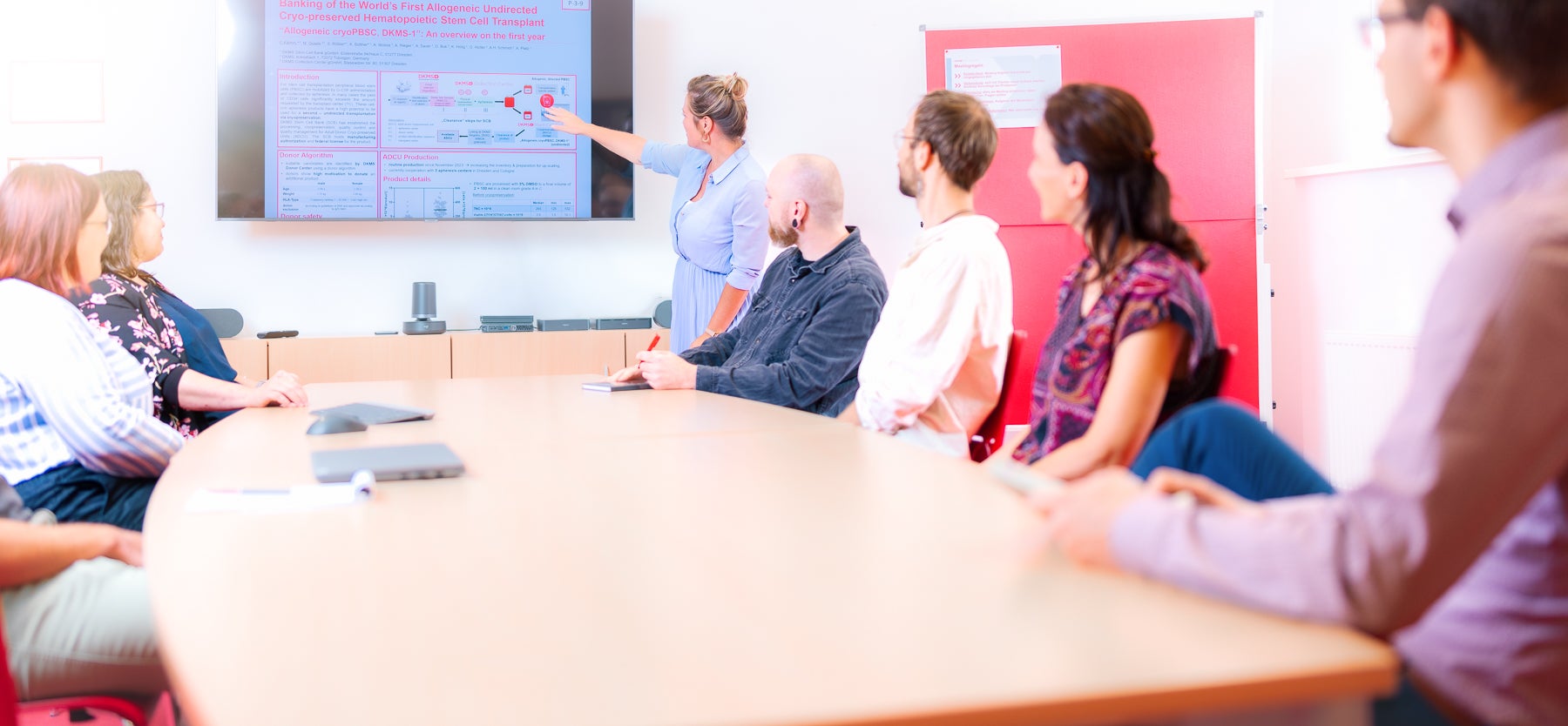 Eine Frau, die auf einen Bildschirm zeigt in einen Raum voller Personen