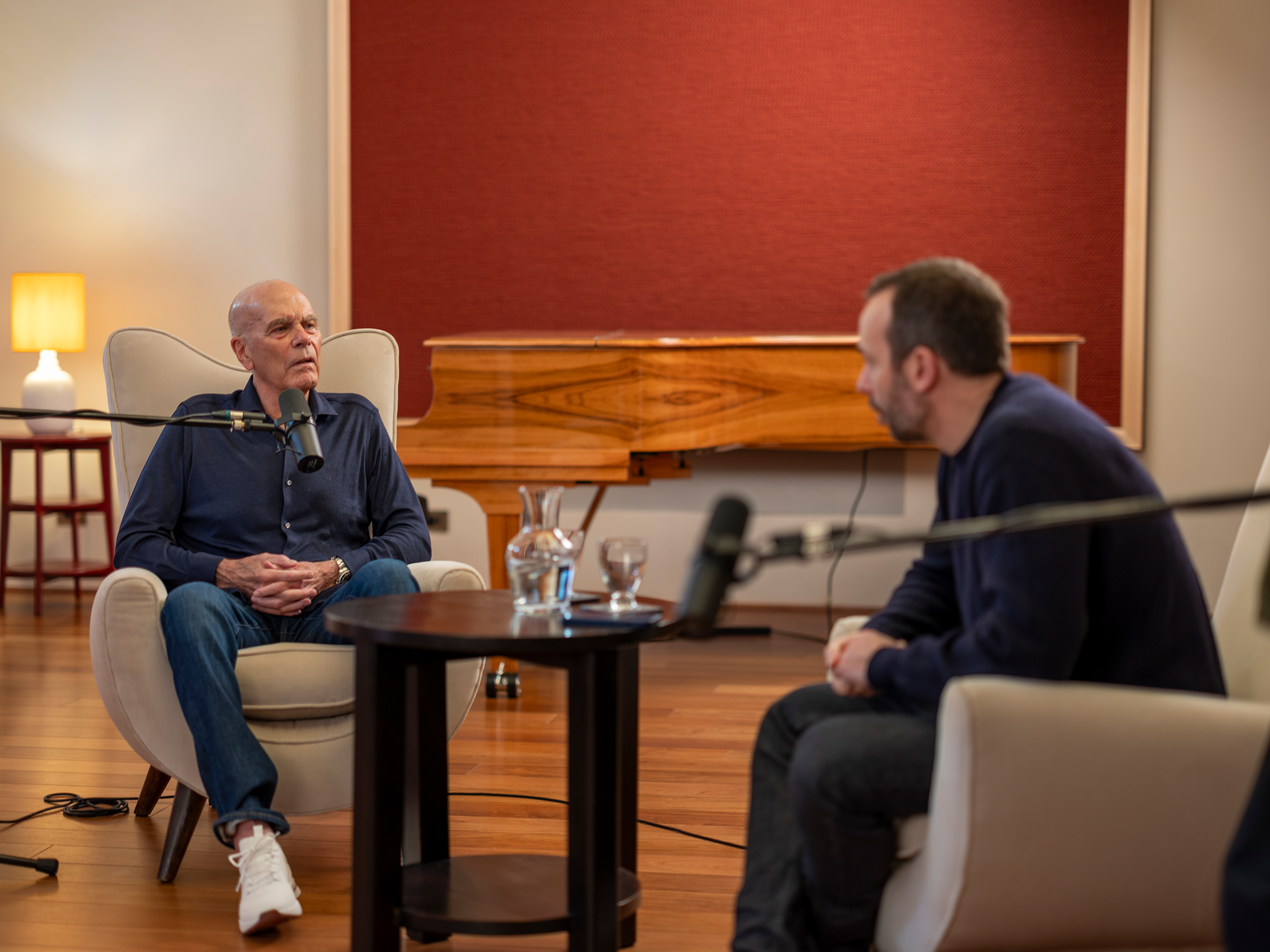 Ein Mann sitzt auf einem Stuhl mit einem Mikrofon vor einem anderen Mann