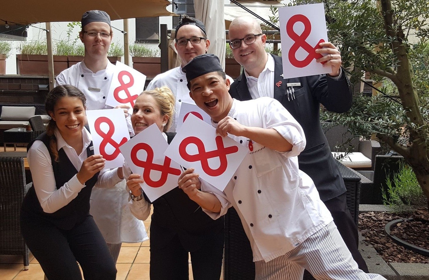 Eine Gruppe von Menschen hält weiße Zettel mit dem Logo der DKMS