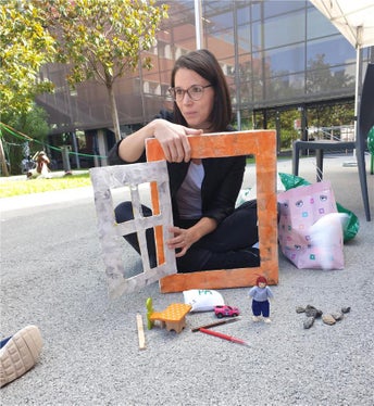 Clara Peretti, QAES-Referentin, zeigt den Kids-Camp-Kindern spielerisch, wie man die Fenster richtig öffnet, um die schlechte Luft mit der guten Luft auszutauschen (Foto: Umweltagentur).