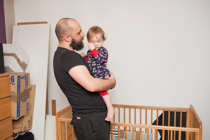A man holds his 18 month old daughter who looks very tired