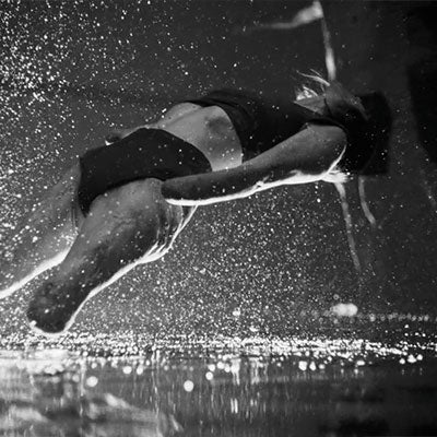 A still from the campaign video of a swimmer with limb differences leaping out of the water.
