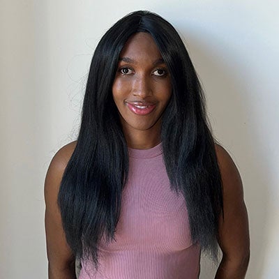 A photo of Abi James Miller smiling. She has long black hair and wears a pink vest top.