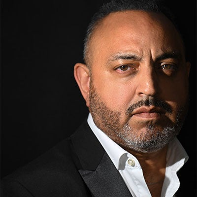 A photo of Dr Amo Raju wearing a white shirt and black blazer. 