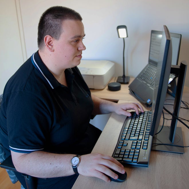 A young man working from a computer at home