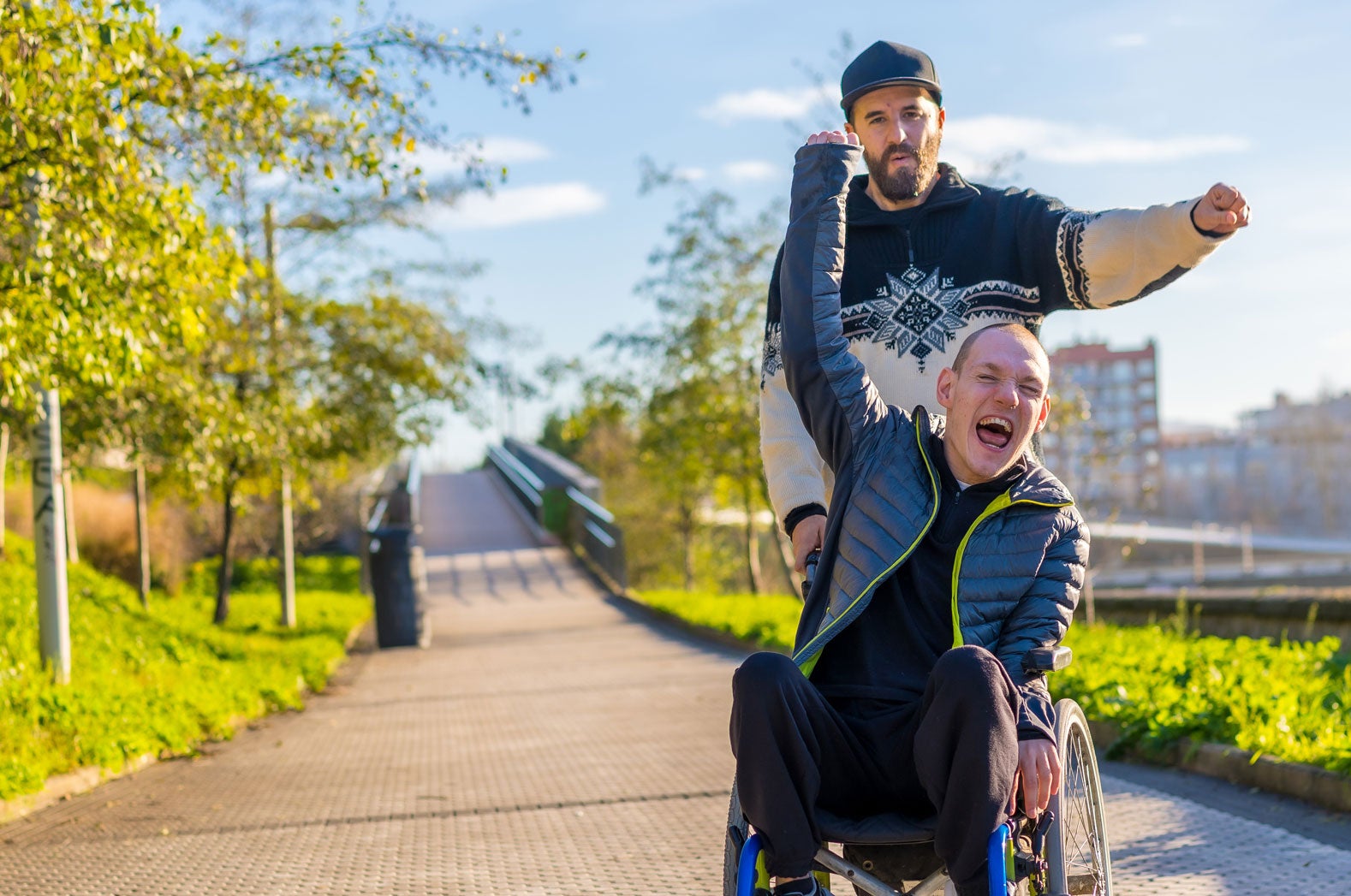 Two friends cheering with arms raised outdoors