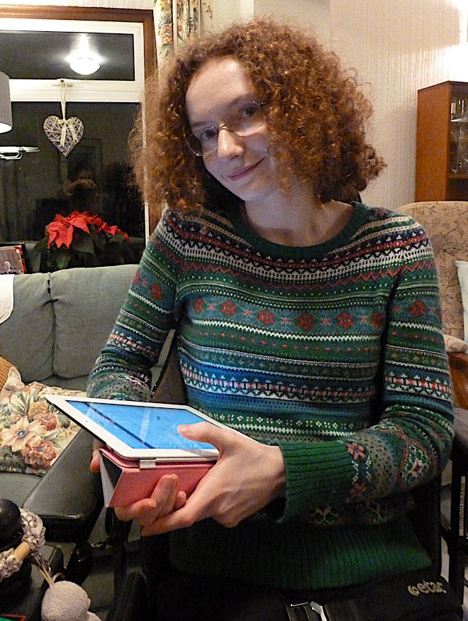 A smiling young woman in a wheelchair looking at an iPad