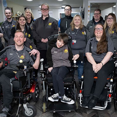 The Happy Smiles Training team smile at the camera, wearing a matching uniform of a grey polo shirt with a smiley face on it.