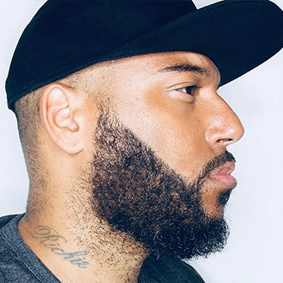 A photo of Richie Brave's side profile. He has a black beard and wears a black cap.