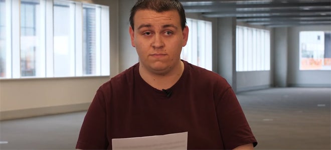 A young man in an empty room reading from a script