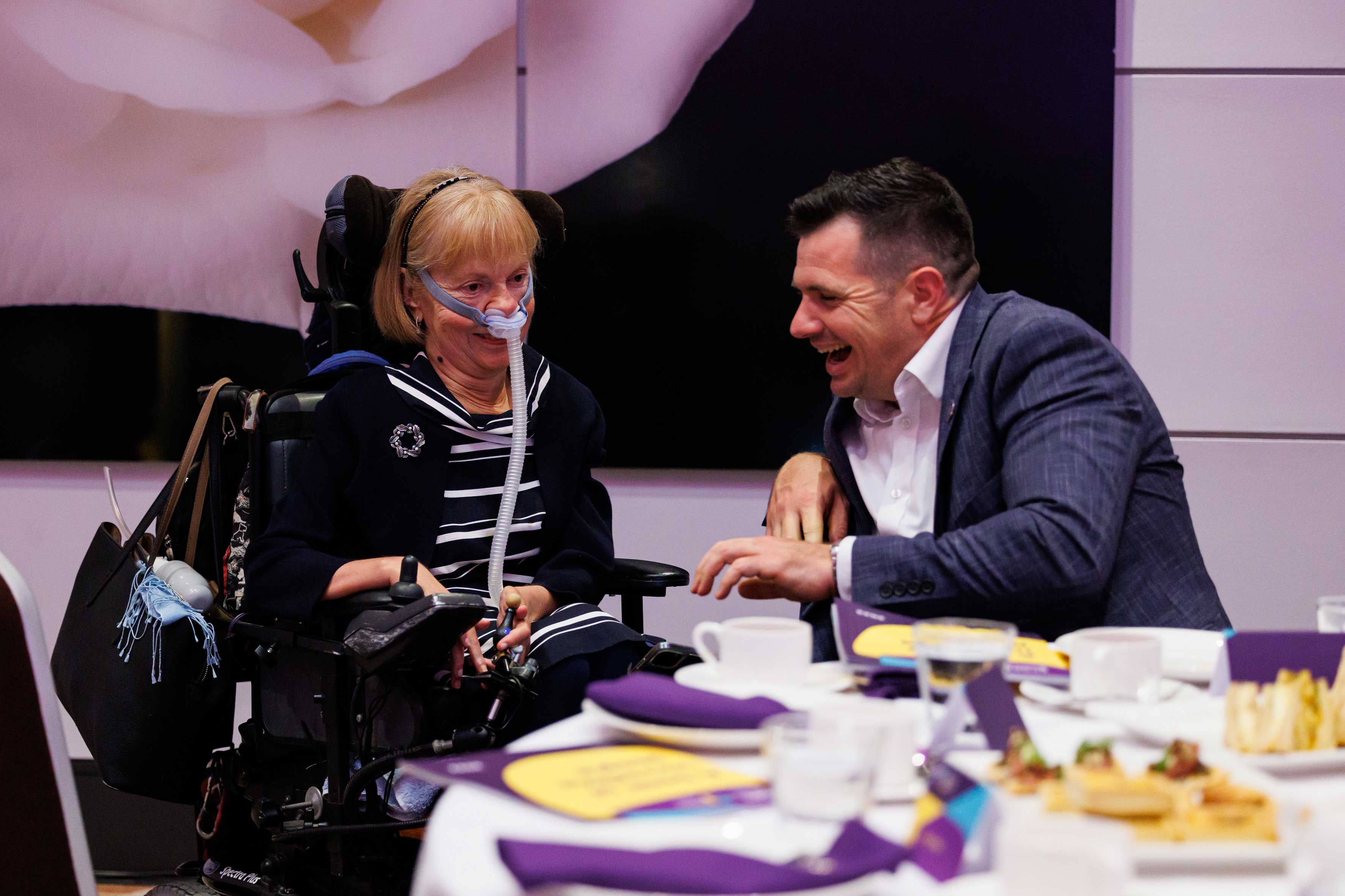 A man and woman in a wheelchair sitting at a table