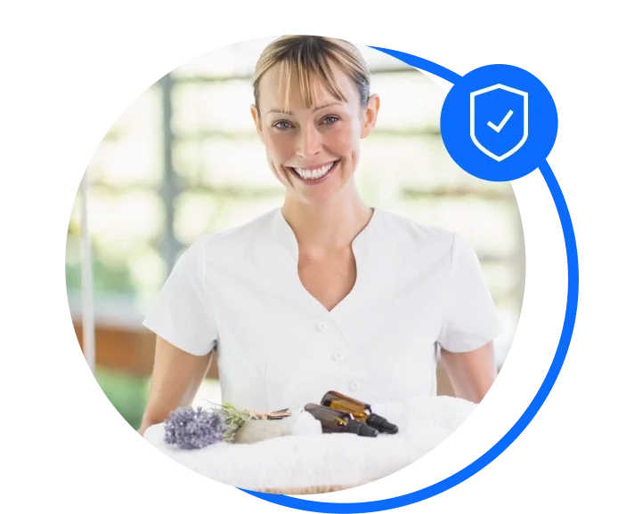 Blonde, female aromatherapist smiling to the camera and holding a towel with lavender and aromatherapy oils