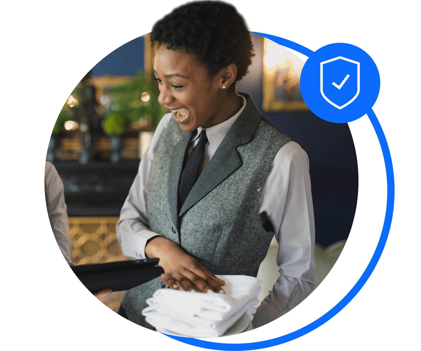 A hotel worker in a grey waistcoat holds towels and smiles after sorting her hotel insurance.