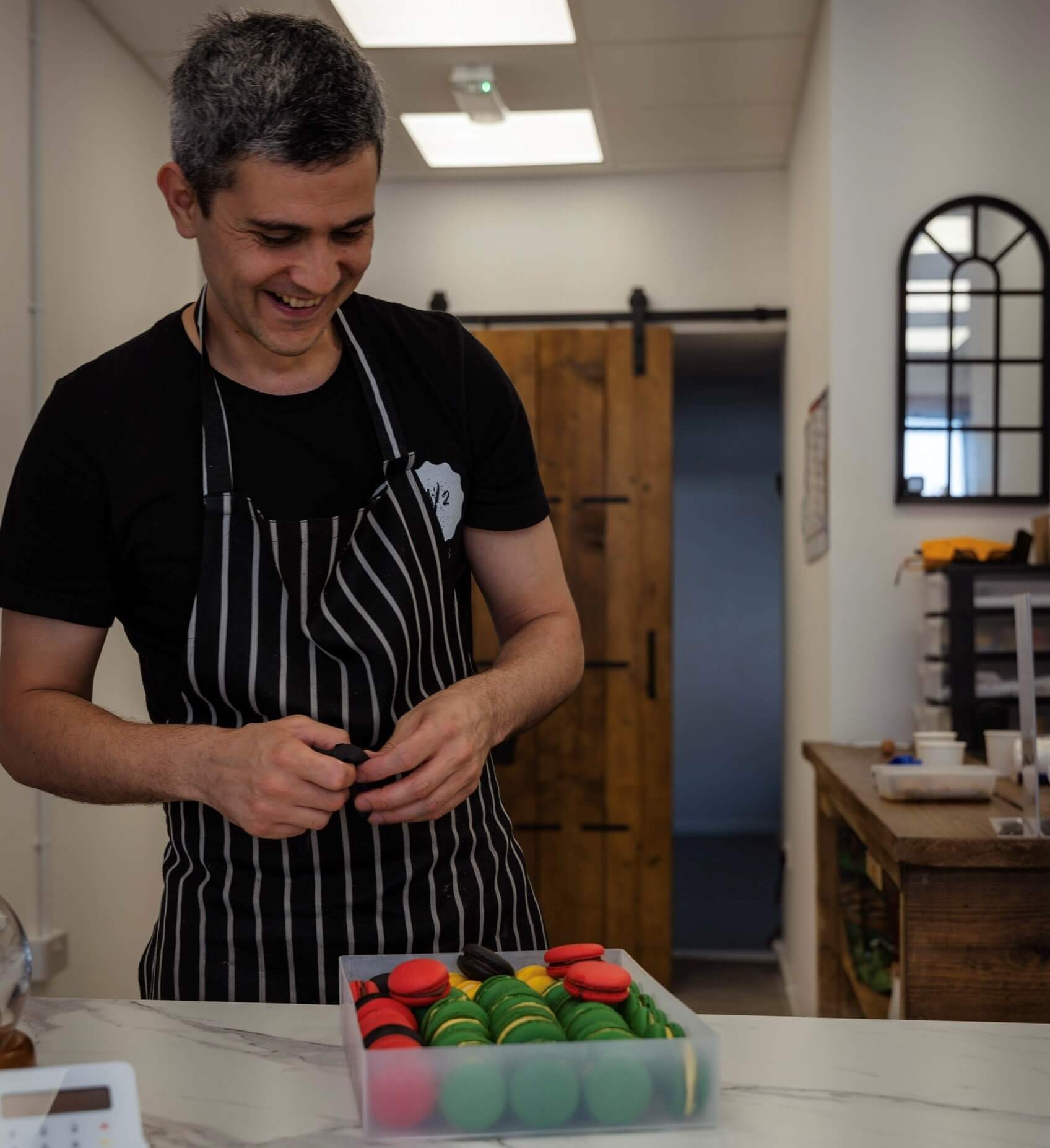 Ned smiles as he arranges macaroons in his workshop.