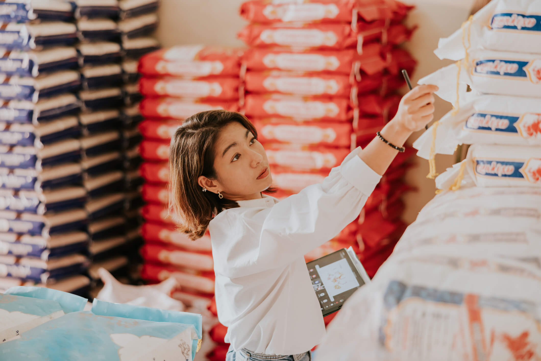 Woman in a backroom stock counting bags of rice