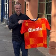 Photo of business owner Dan Lindsay who owns Taquero in Nottingham. He's holding a orange Bionic football shirt and smiling to the camera.