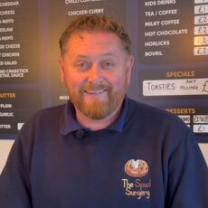 Adam, owner of a small business called Spud Surgery standing in his business and smiling to the camera